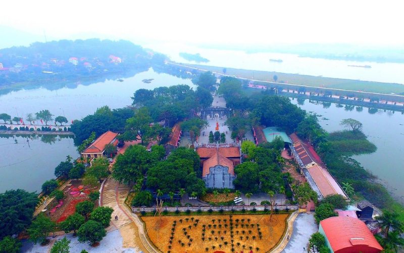 Vue aérienne du temple Kiep Bac, entouré de lacs et de verdure. On distingue les toits traditionnels en tuiles rouges, les allées bordées d’arbres et les jardins soigneusement aménagés, créant un cadre paisible et majestueux au bord de l’eau