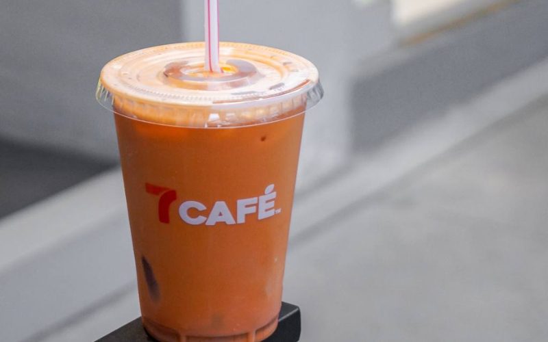 Gobelet de thé thaï glacé 7 Café de 7-Eleven, boisson orange crémeuse avec paille, posé à l’extérieur du magasin
