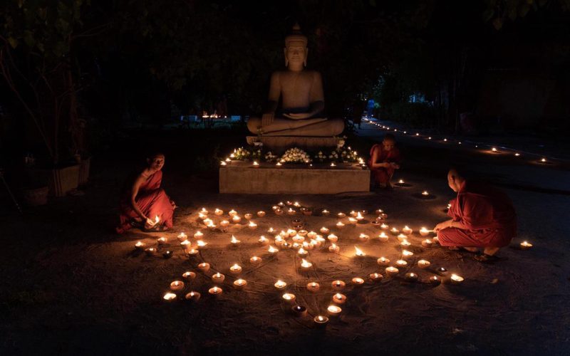 Des moines bouddhistes allument des lampes à huile autour d’une statue de Bouddha lors d’une cérémonie nocturne pendant le festival de Khao Phansa