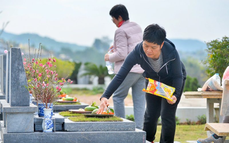 Une femme vietnamienne dépose des offrandes sur la tombe d’un proche, en hommage aux ancêtres pendant la fête du Vu Lan, une tradition spirituelle et familiale importante au Vietnam