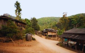 Village Lahu traditionnel niché au cœur des montagnes, avec des maisons en bois alignées le long d’un chemin de terre