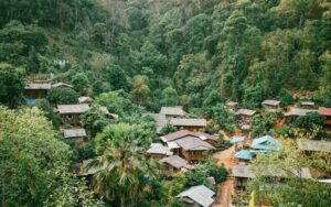 Vue aérienne d'un village Karen niché au cœur de la forêt tropicale, avec des maisons traditionnelles en bois entourées de végétation luxuriante