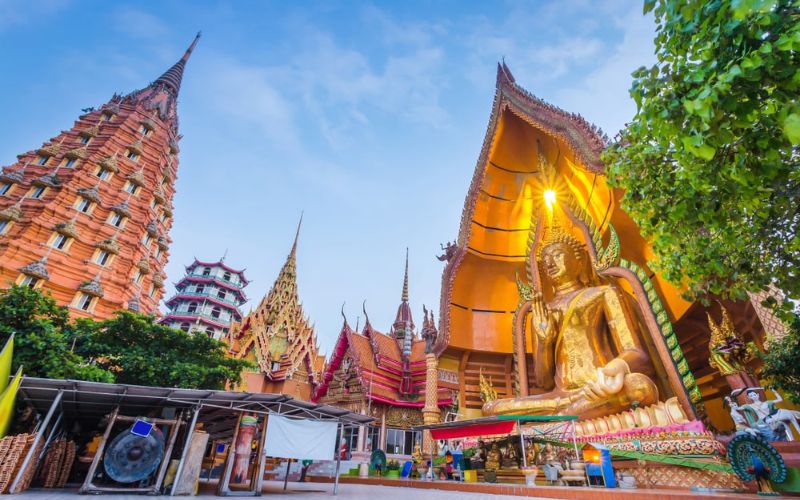 Temple Wat Tham Suea, mettant en valeur une grande statue de Bouddha dorée et des structures architecturales ornées sous un ciel clair