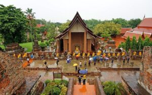 Vue du temple Wat Yai Chai Mongkhon à Ayutthaya par temps de pluie, avec des visiteurs se promenant sous des parapluies